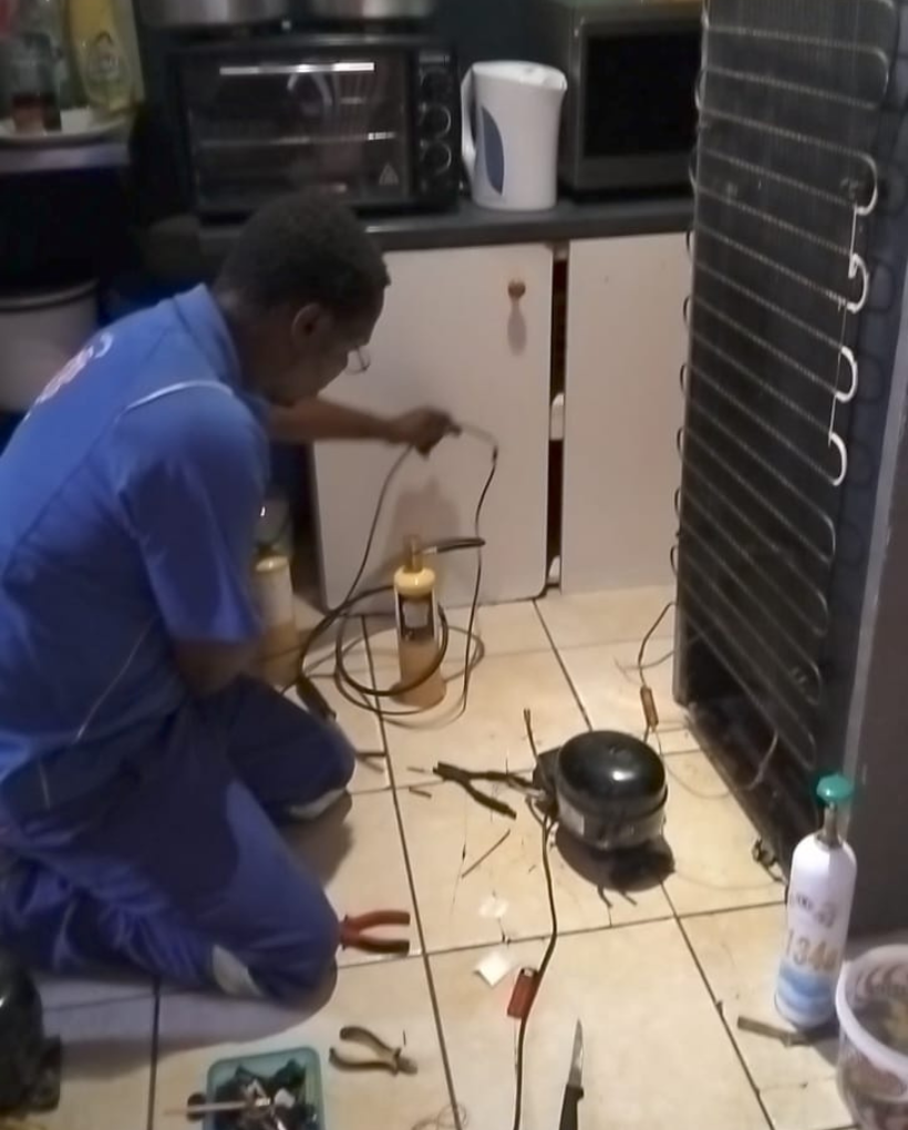 Hisense fridge repair technician servicing a refrigerator in Cape Town, South Africa.